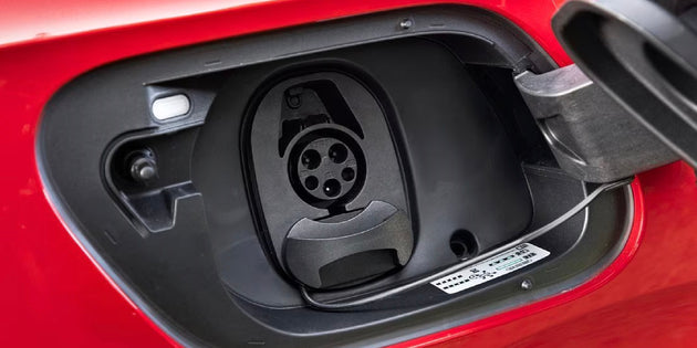 Charging connector plugged into the charging port of a red electric car