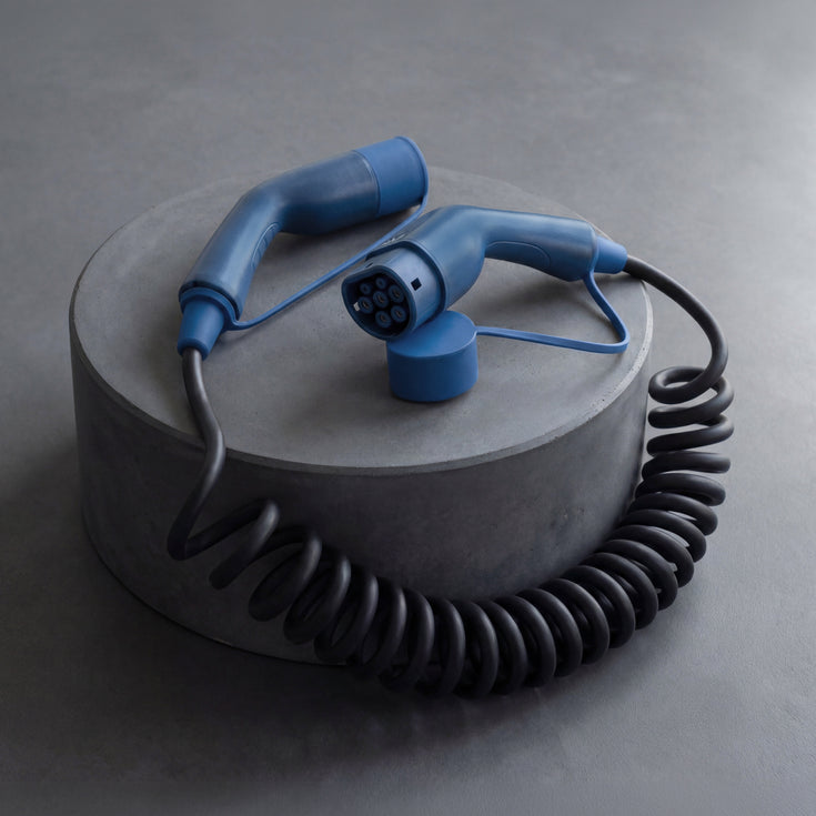 Voldt® coiled EV charging cable displayed on a grey concrete plinth
