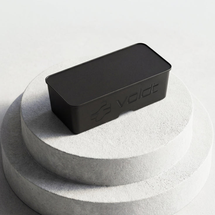 Closed black Voldt® EV cable storage box displayed on a stone plinth