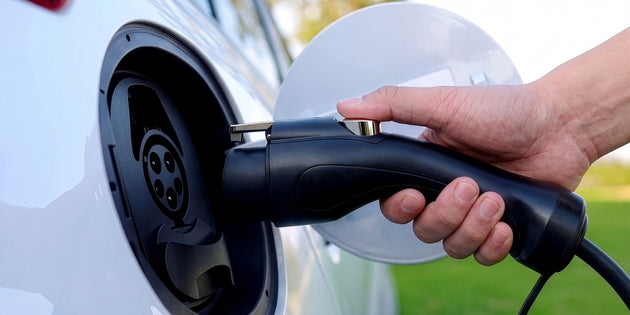 Hand plugging the Type 1 connector into the charging port of a white electric car